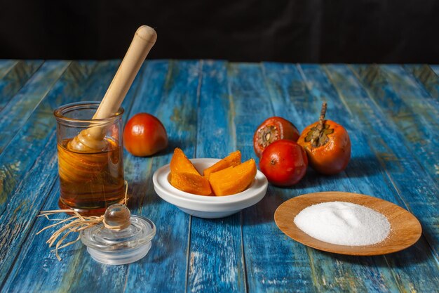 Chontaduro, exotisch tropisch fruit, gesneden met zout en honing naast rauwe chontaduros op een rustieke blauwe houten tafel. Bactris gasipaes