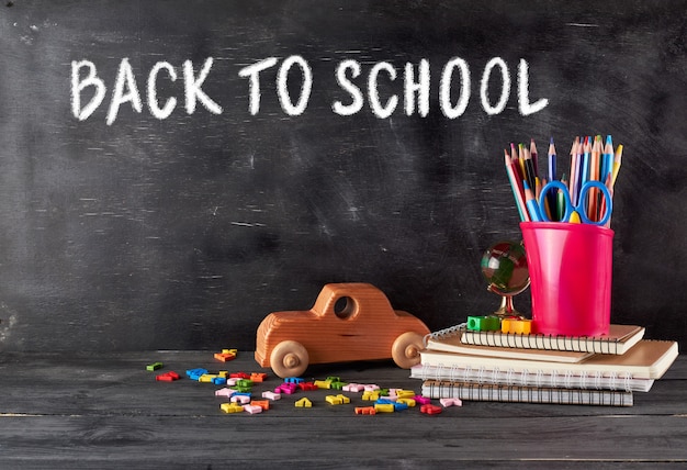 Chool supplies: notebook, pencils, scissors and a wooden retro toy car