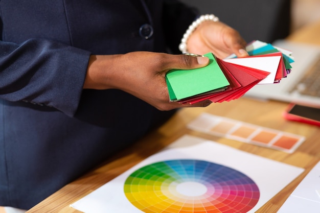 Choosing color. Close up of interior designer wearing bracelet choosing color for apartment