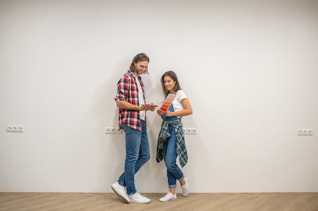 Choosing color. Young couple discussing the color for walls and looking involved