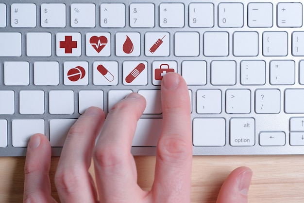 Choosing the necessary medical care online. Hand on the keyboard with signs.