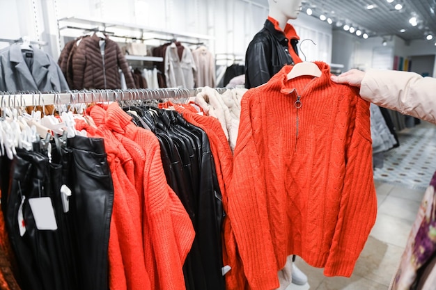 Choosing an orange sweater on a hanger