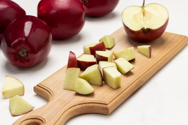 Chopped apples on cutting board Ripe red apples on table Close up White background