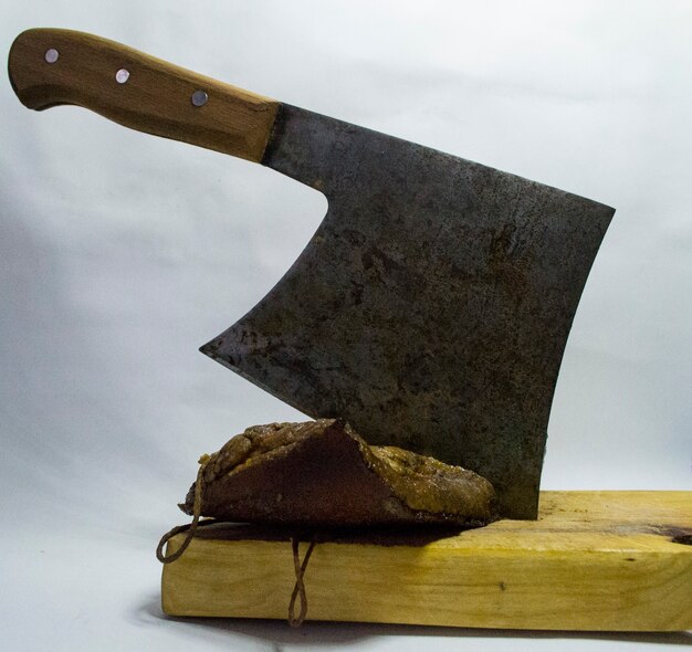 白い背景の上の鉄の手斧と木の板に刻んだベーコン