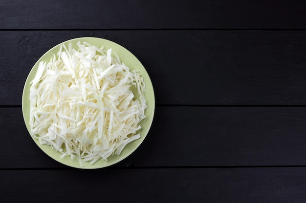 Chopped cabbage on dark background White cabbage on green plate Fresh vegetables on black boards Copy space