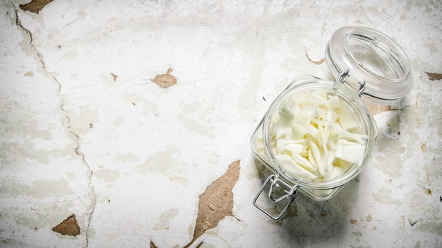 The chopped cabbage in a glass jar. On rustic background.