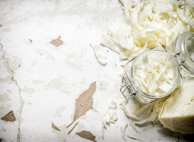 The chopped cabbage in a glass jar. On rustic background.