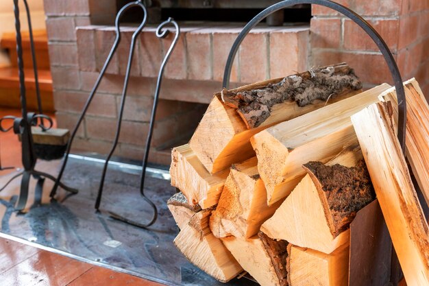 Chopped firewood stacked in woodpile against background of fireplace