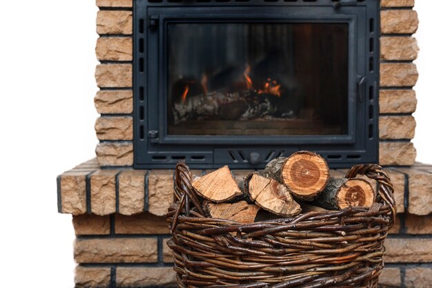 Chopped firewood in a wicker basket on the background of a decorated fireplace