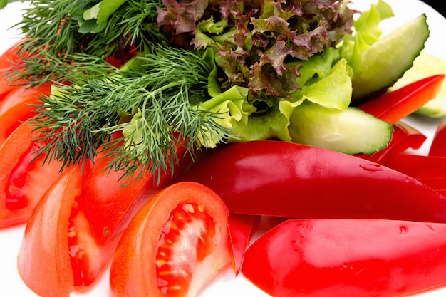 Нарезанные свежие овощи и зелень на тарелке