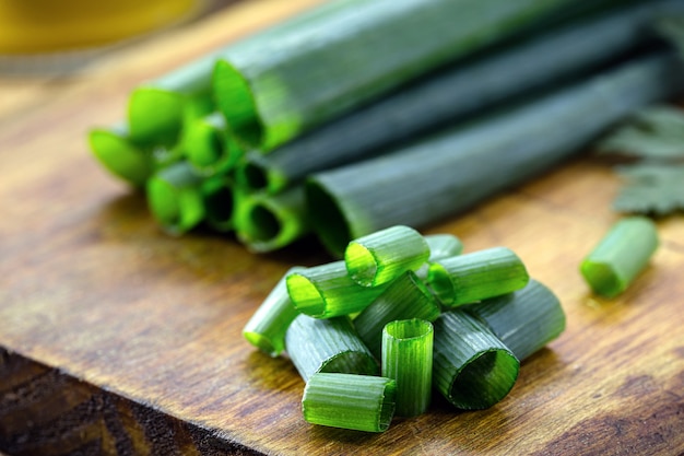 Chopped green onions on wooden kitchen board, culinary ingredient in close-up.