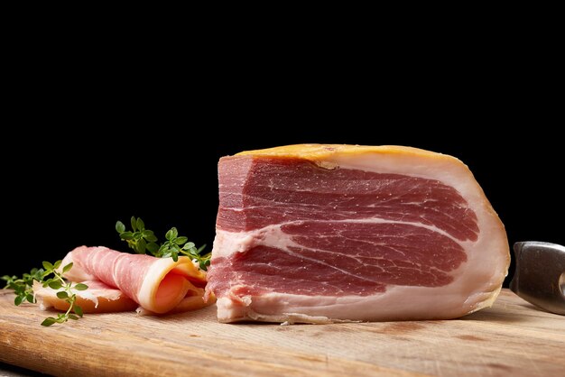 chopped into pieces of prosciutto on a brown wooden board close up