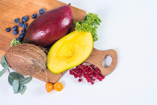 Chopped mango on two halfs with fruits on white