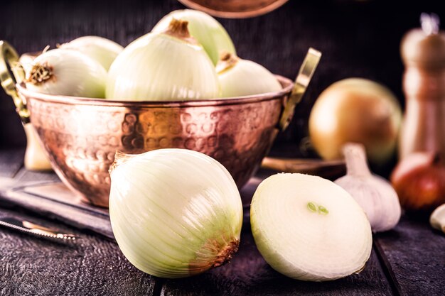 Chopped onion cut in half, with copper cooking utensils in the surface, rural or rustic cuisine