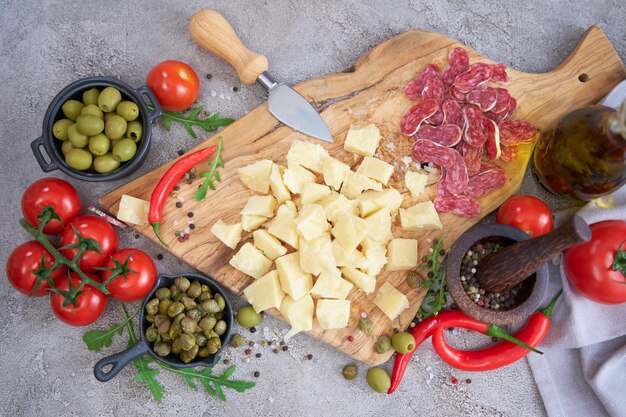 Chopped Parmesan cheese and vegetables on grey table at domestic kitchen