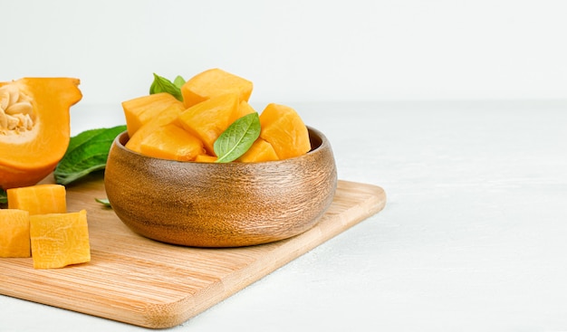 Zucca tritata in un piatto di legno su un tavolo bianco, cucinando la zucca