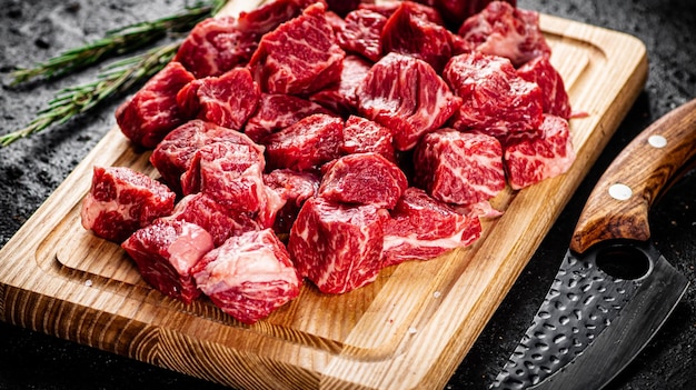 ローズマリーとナイフでまな板に刻んだ生の牛肉