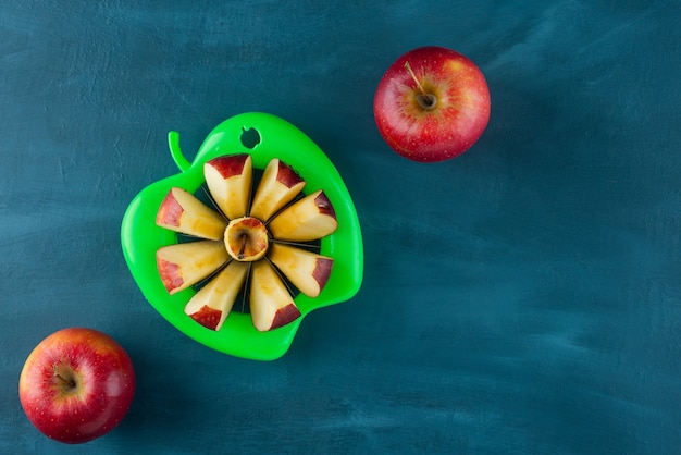 Chopped red apple placed on a dark-blue table.