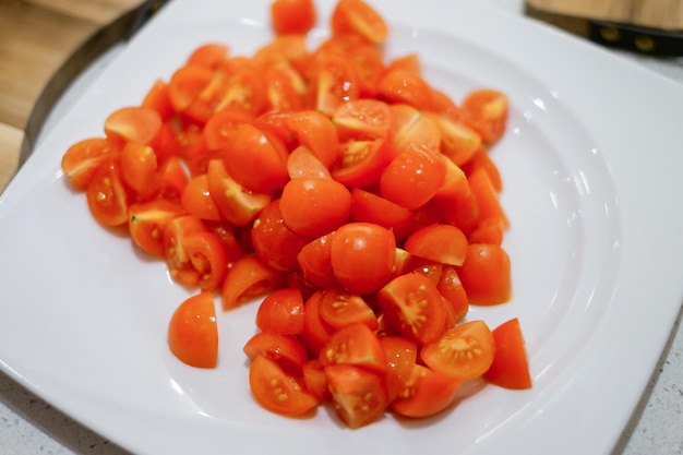 Chopped tomato on a white plate People making salad together awaiting guests Concept of home cooking healthy food