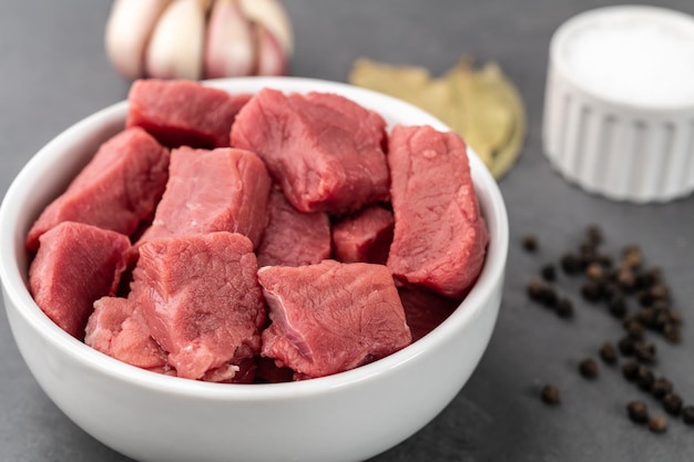 Chopped topside meat in a bowl with seasonings over stone background