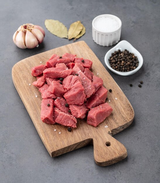 Chopped topside meat on wooden board over stone background with seasonings