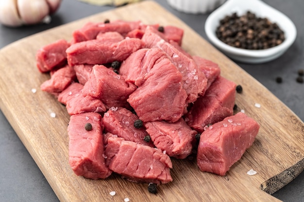 Chopped topside meat on wooden board over stone background with seasonings