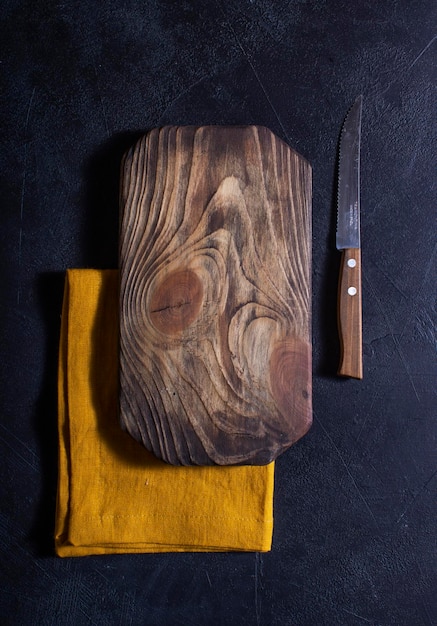 Chopping board for cutting vegetables and food with a knife rustic dark brown background with natural wood texture