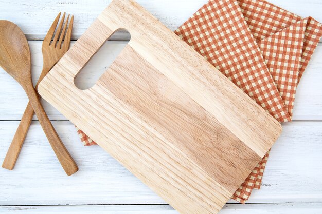 白いテーブルに木製のフォークとスプーンでボードとテーブルクロスをチョッピング