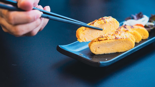 Chopstick hold tamagoyaki, soft focus zoete omelet in het japans