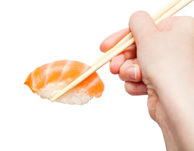 Chopsticks hold nigiri sushi with salmon close up