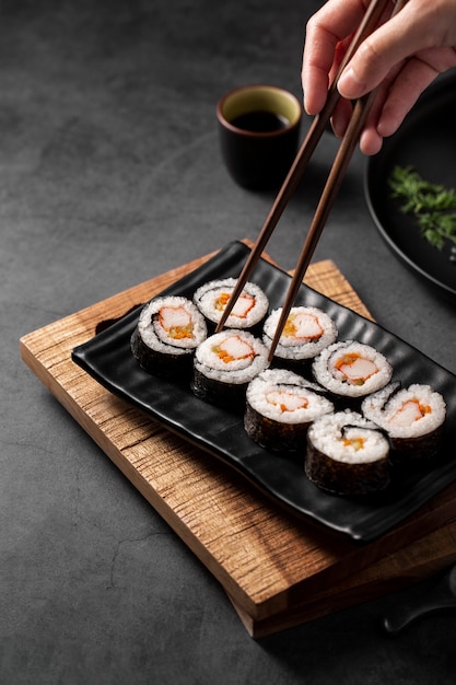 Bacchette raccogliendo involtini di sushi maki