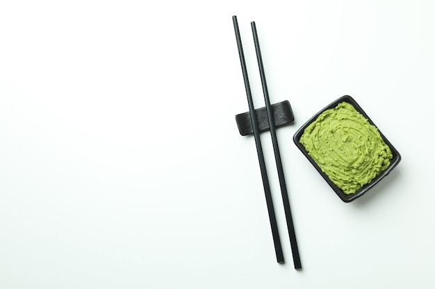 Chopsticks and wasabi sauce on white