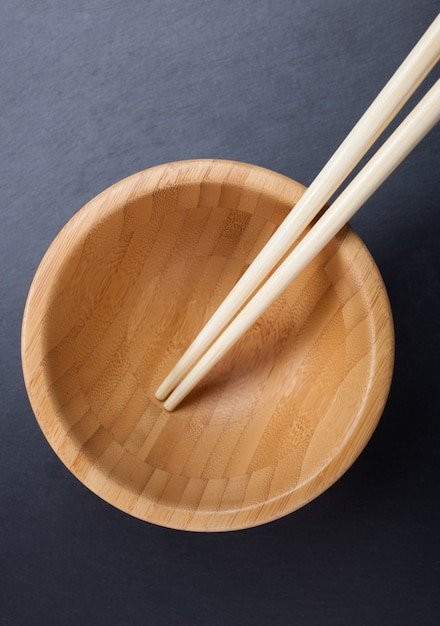 Chopsticks with empty bowl on slate.