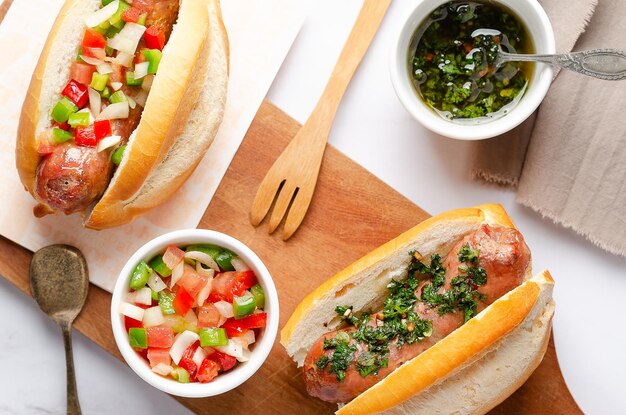 Foto choripanes con chimichurri e salsa criolla argentina su una tavola di legno