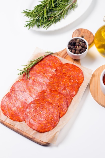 Photo chorizo sausage and salami, thin cut. spanish salami on the wood background with spices