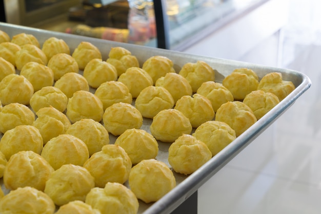 Choux cream in bakery tray on table.