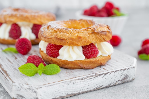 Choux pastries Choux rings with cream and raspberries dusted with powdered sugar