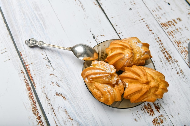 Chouxgebakje en lepel, op houten achtergrond. Sluit Choux Cream. Met een metalen lepel en vork op de achtergrond