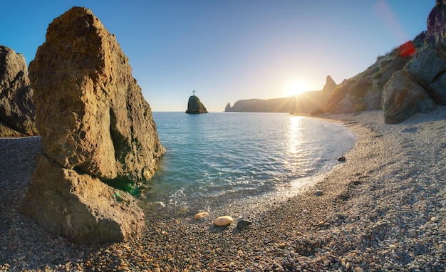 Christ cross and high rock on sea shore