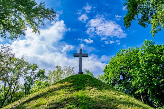 Foto christelijk kruis op een heuvel tegen een blauwe lucht met witte wolken