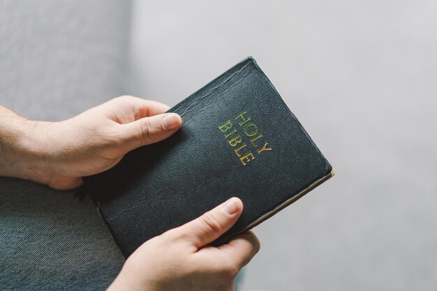 Christelijke man houdt heilige bijbel in handen Lezen van de Heilige Bijbel in een huis Concept voor geloof, spiritualiteit en religie Vrede, hoop