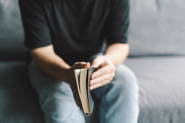 Christelijke man houdt heilige bijbel in handen Lezen van de Heilige Bijbel in een huis Concept voor geloof, spiritualiteit en religie Vrede, hoop