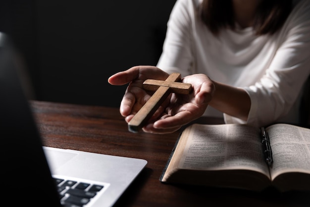 Christelijke online technologie concept Handen bidden van christen met digitale computer laptop Online live kerk voor zondag dienst Aziatische katholieke man lezen de Heilige Bijbel boek en online studie