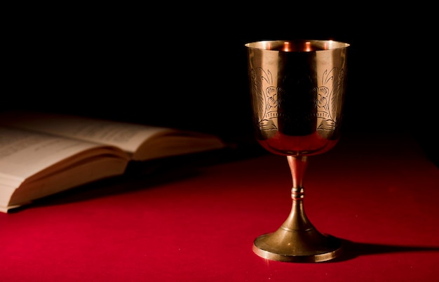 Photo christian chalice on altar open bible with strong red background