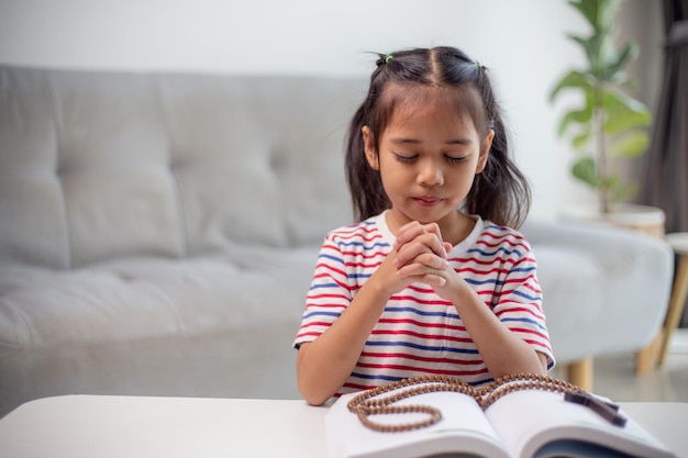 Христианская концепция Маленькая азиатская девочка молится, удерживая крест Концепции надежды веры Христианство религия