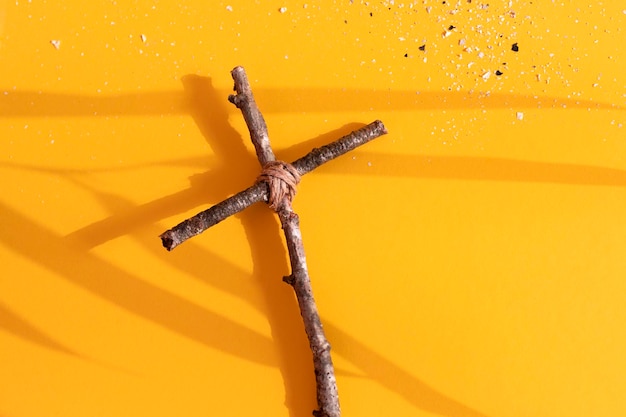 Christian cross and ashes on yellow background