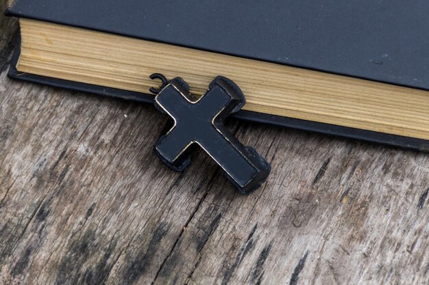 Christian Cross and Holy Bible on old wooden table. Religion concept