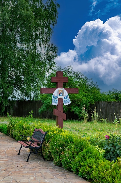 Foto croce cristiana con un'icona contro un cielo blu con nuvole