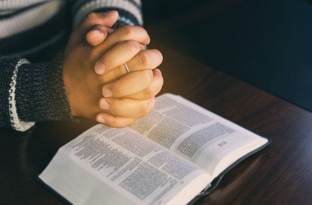 Foto mani cristiane mentre pregano e adorano per gesù. persone cristiane che pregano mentre le mani adorano su una bibbia. imparare la religione.