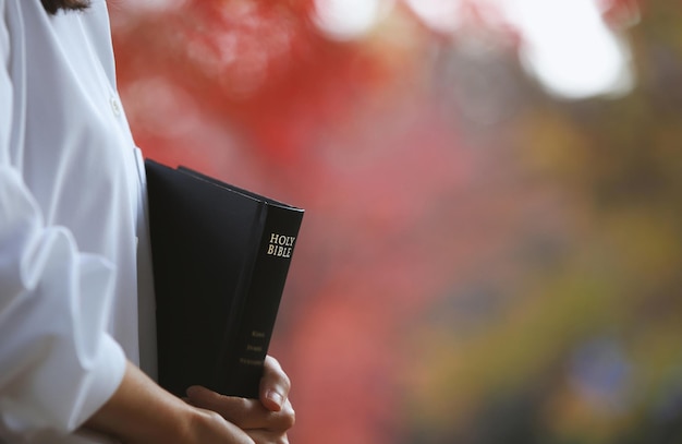 Foto un cristiano che tiene la sacra bibbia e predica il vangelo di gesù cristo e uno sce di strada autunnale